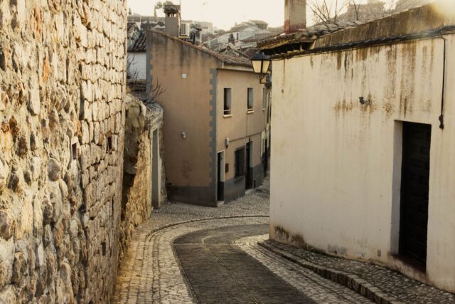 Stradă îngustă pavată cu piatră, luminată de soarele dimineții, într-un oraș liniștit